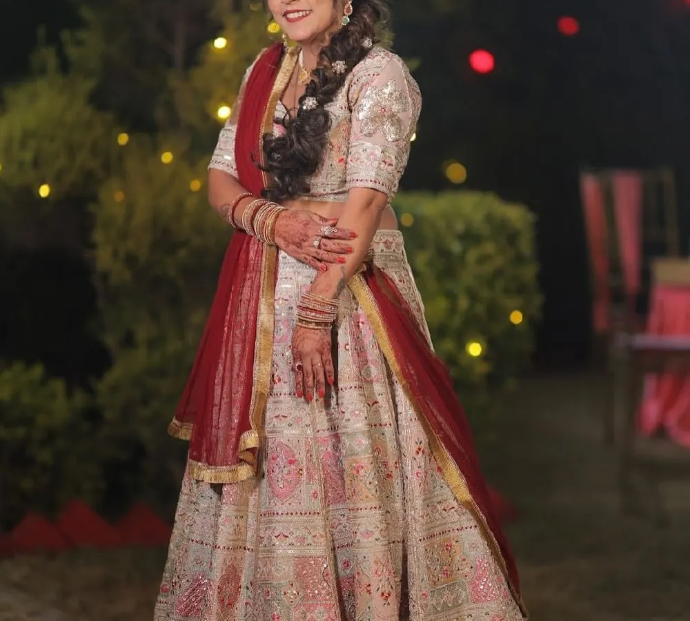 For me, a bridal lehenga should be a masterpiece. This stunning white and red lehenga features intricate embroidery and a classic silhouette, designed to make my bride feel like royalty on her special day.
