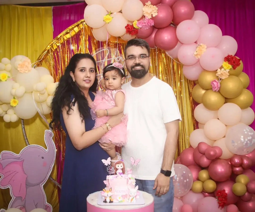 A classic family portrait during a first birthday celebration. I focus on capturing the whole family together, smiling against the beautiful decorations of the special day.