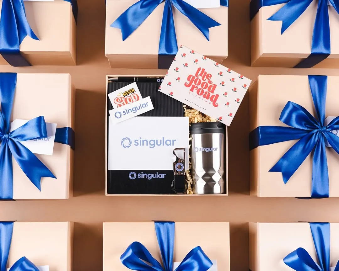 We love seeing our workshop filled with beautifully branded boxes ready for dispatch. This flat lay shows a batch of custom welcome kits for our client Singular, each packed with care and tied with their signature blue ribbon, ensuring a consistent and professional brand experience.