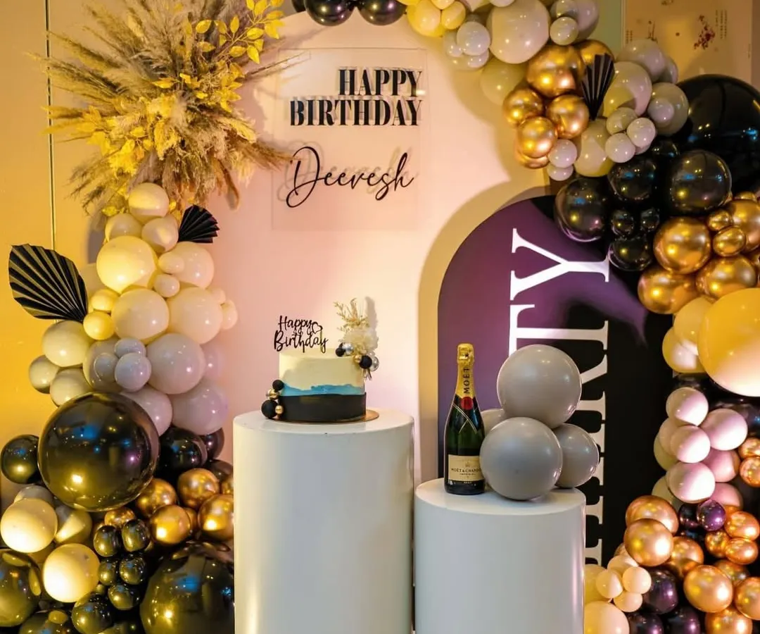 This is a perfect example of a sophisticated birthday setup for an adult. I used a classic black, gold, and white color scheme with a modern arched backdrop, a custom acrylic sign, and elegant white pedestals for the cake and champagne. The dried pampas grass adds a trendy, textural element.
