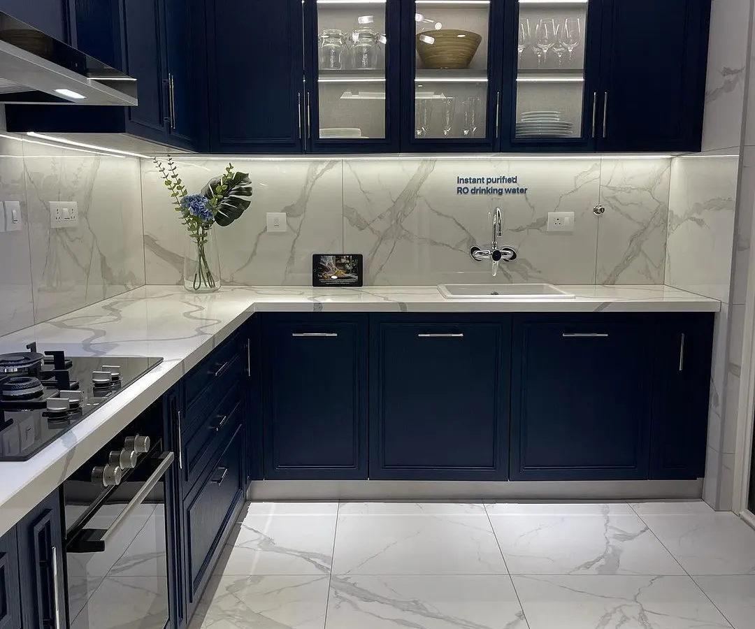 This modern kitchen features sleek navy cabinetry, marble patterned surfaces, and integrated lighting. It's a perfect example of the curated, high end interiors I look for in a property.