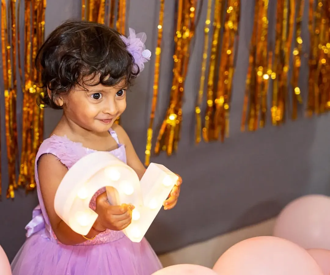 For this little one's birthday photoshoot, we created a magical setting with soft pink balloons and shimmering gold streamers. I love capturing these milestone portraits, focusing on the birthday girl's bright eyes and happy smile as she celebrates her special day.