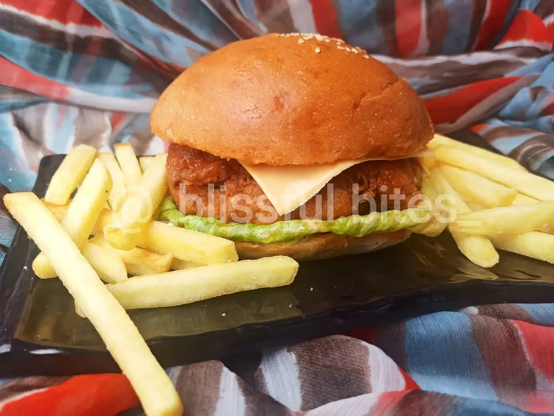 My bestseller, the homemade Chicken Zinger Burger. It features a crispy, juicy chicken patty, fresh lettuce, and a slice of cheese, served with a side of golden french fries.