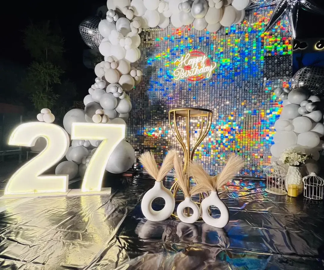 For a 27th birthday that needed to be extra glamorous, we designed this stunning silver sequin backdrop. The glowing marquee numbers and modern pampas grass decor created a chic, photo-perfect spot for a night of celebration.