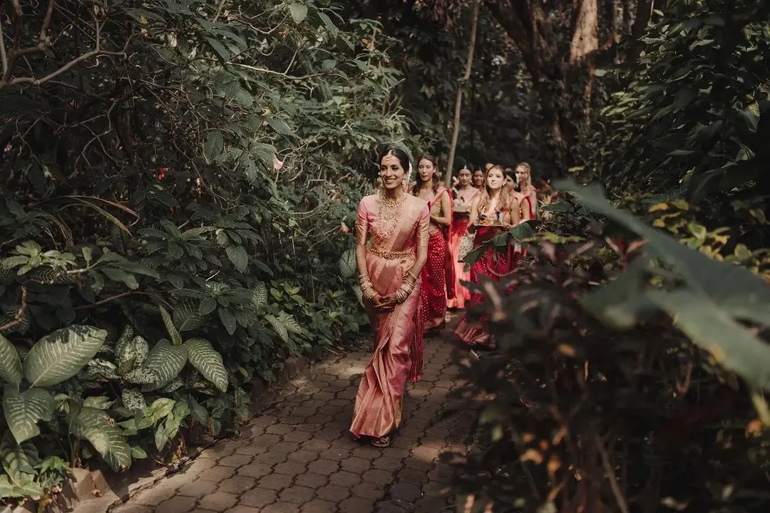 The arrival of the bride is always the most poetic moment. Here, Vidya and her girls walk amidst the rustling leaves and dancing sunlight at the Taj Westend, a bridal entry that perfectly captures the anticipation and joy we love to orchestrate.