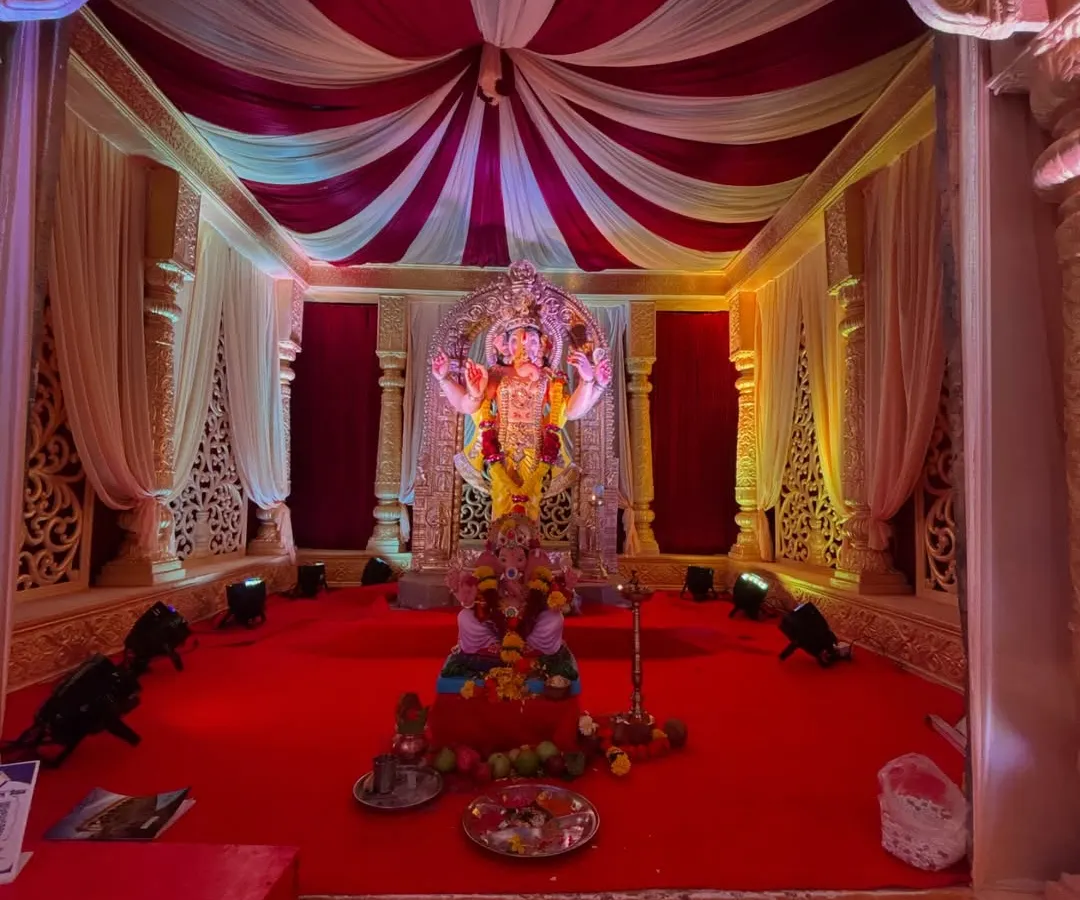 A classic Ganesh Chaturthi mandap I designed. The setup includes rich red and white drapes, intricate side panels, a raised platform for the idol, and professional lighting to create a divine atmosphere for Bappa.