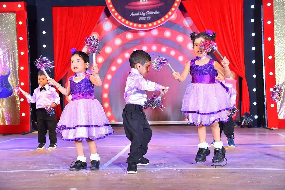 Young performers full of energy on stage in two-tone purple and lilac dresses, complete with matching accessories for their annual day celebration.