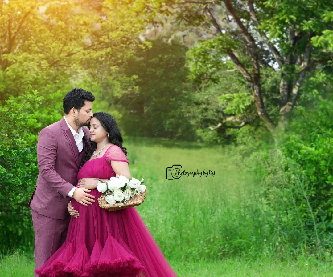 A tender moment between expecting parents, captured in our private outdoor garden. The vibrant magenta gown stands out beautifully against the lush greenery, and the golden hour light adds a warm, romantic glow to this pregnancy portrait.