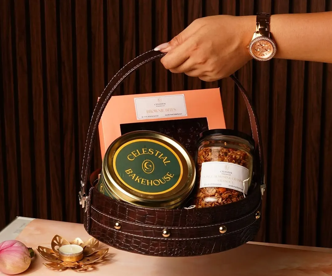 This is what a gift of love looks like. Our Raksha Bandhan gift basket, held here, is filled with our handmade eggless brownies, crunchy granola, and signature cookies, all packed into a beautiful, reusable leatherette basket.