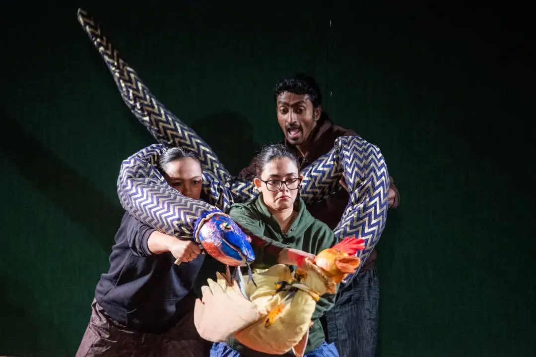 Experience the drama and artistry of our own production, 'Be Yourself'. In this powerful scene, puppeteers work together to create a tense encounter between a large, fabric snake and a small bird, showcasing dynamic storytelling through large-scale puppetry.