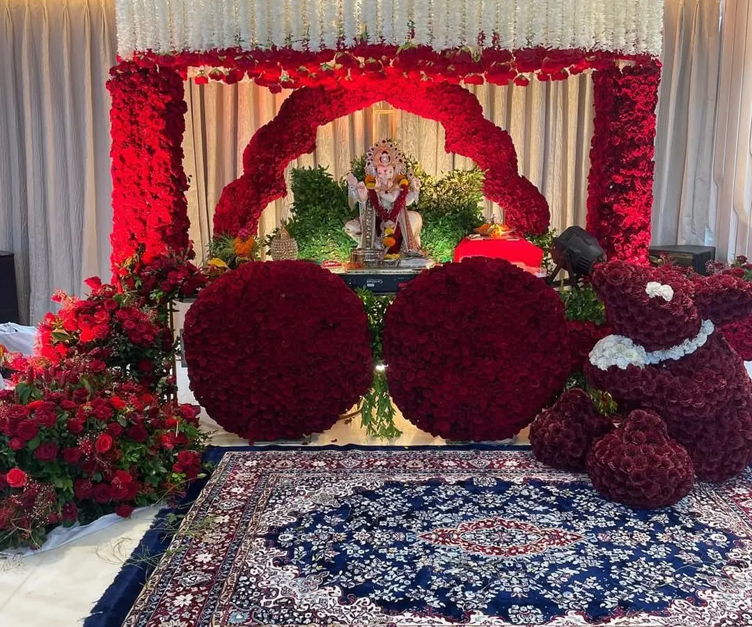 For an intimate home celebration, we designed this stunning floral mandap using thousands of red roses. The mirrored floor adds a touch of glamour, reflecting the vibrant decor and creating a truly immersive worship space.