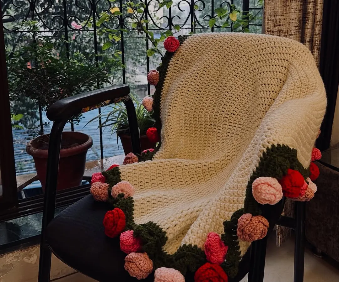 This is my rose bouquet blanket, a true passion project. I stitched 32 individual roses onto this cozy, cream-colored blanket, creating a piece that is both functional and a work of art. It’s perfect for draping over a chair or snuggling up with.