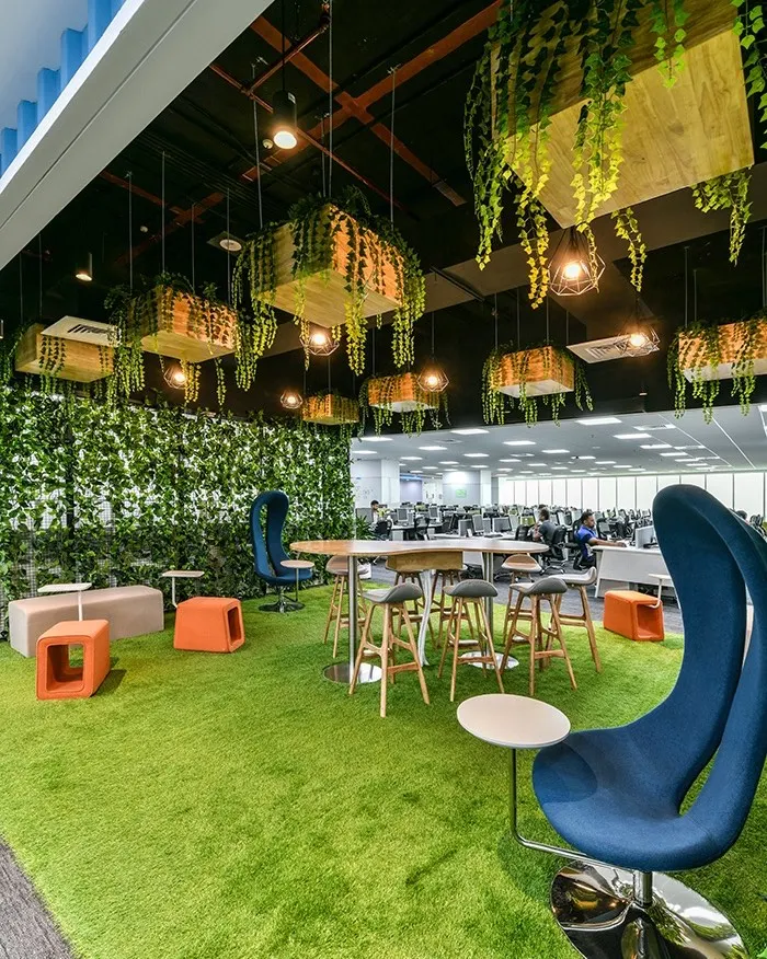 We love bringing the outdoors in. This biophilic breakout zone features an artificial grass floor, unique high-backed chairs, and planters suspended from the ceiling, creating a refreshing park-like atmosphere right inside the office.