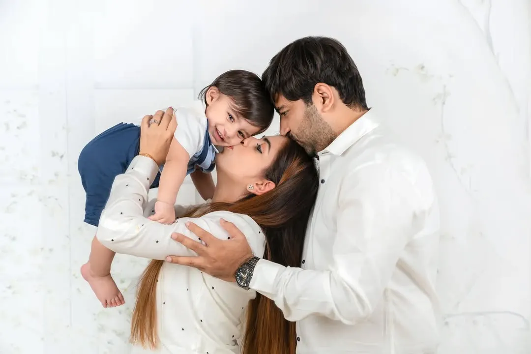 A tender, candid moment capturing the pure love of a family. A mother and father gently kiss their baby, creating a memory of warmth and connection that will last forever.