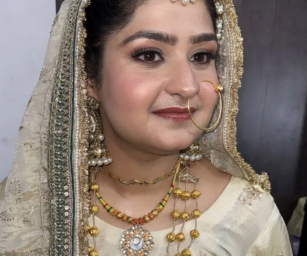A detailed close-up of our elegant bridal makeup. This look features soft, blended eyeshadow, precise eyeliner, and a natural blush, all designed to enhance her features while complementing the intricate gold jewelry and attire.