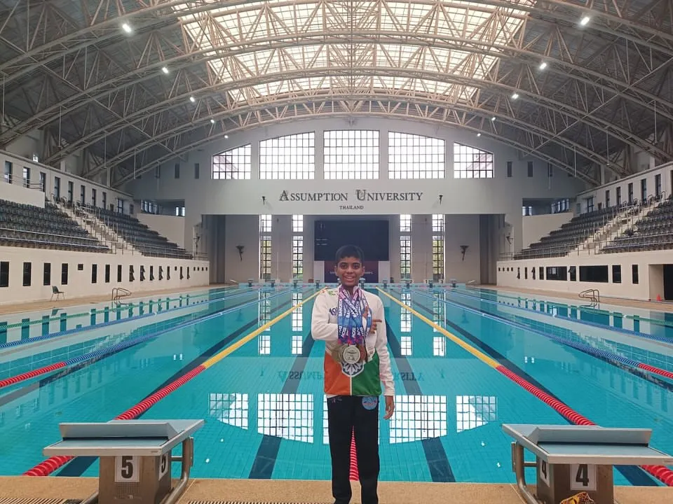 This is the result of dedication. Here is our swimmer, Bryce, proudly displaying his gold, silver, and bronze medals at the Asian Open Schools Invitational Swimming Championship in Thailand. This image captures the proud moment of achievement at a world-class swimming facility, a goal we help our competitive swimmers reach.