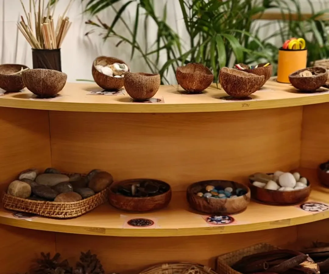 Our environment is the third teacher. We intentionally curate shelves with natural, open-ended materials like stones, pinecones, and seed pods. These "loose parts" invite children to imagine, create, and construct their own stories, transforming simple objects into anything their minds can conceive.