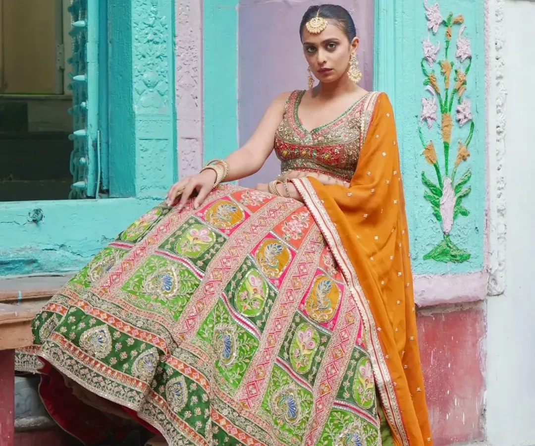 For a look that’s pure heritage with a vibrant twist, this multi-panelled lehenga is it. The rich green and pink panels are detailed with traditional motifs, making it a stunning choice for a sangeet or wedding day.