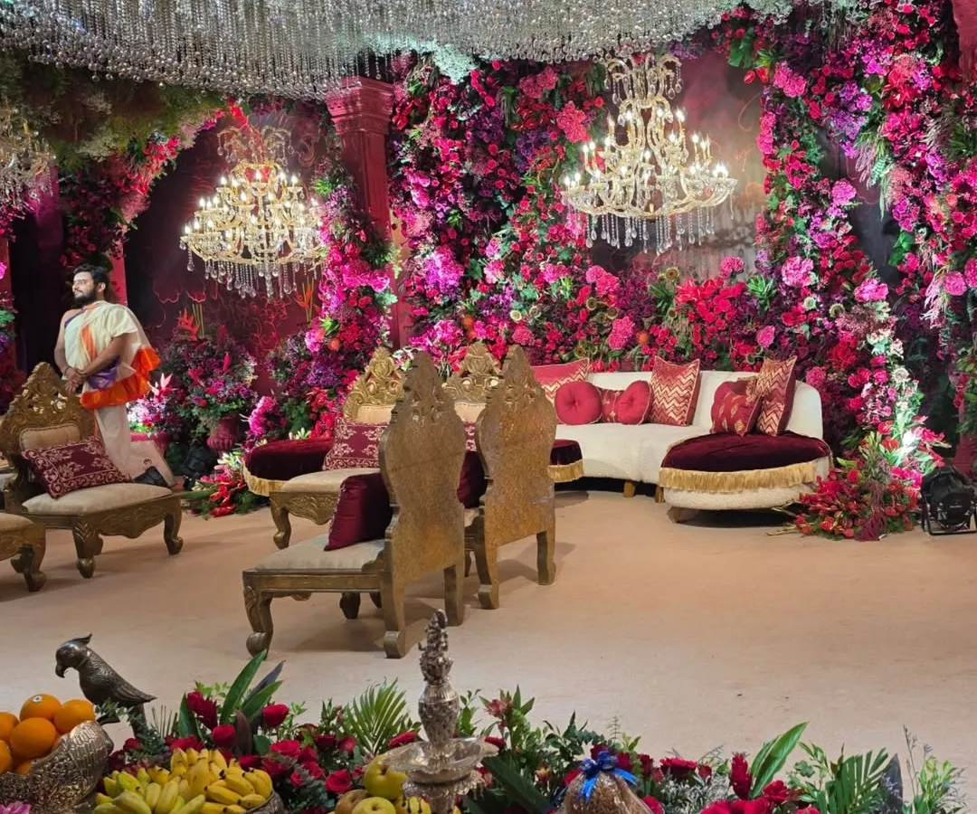An immersive look into a lavish wedding reception stage, creating a magical floral cave effect. I used thousands of pink and red flowers, complemented by crystal chandeliers and elegant seating to create a truly grand and romantic atmosphere.
