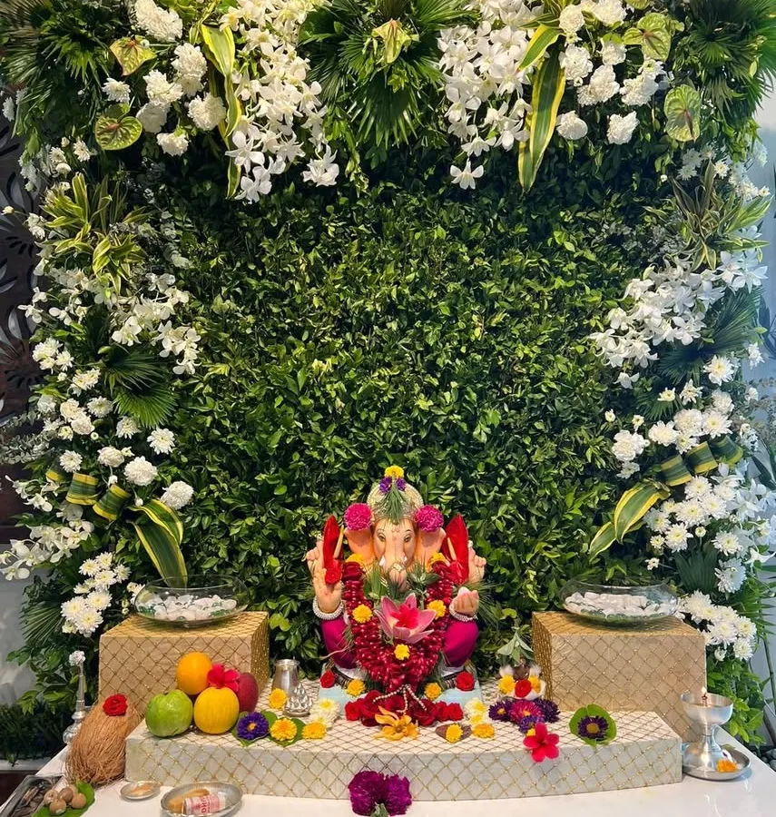 This modern and elegant Ganpati backdrop features a dense wall of fresh greenery, accented with clusters of white orchids and other exotic white flowers. It’s a perfect example of how we blend contemporary style with traditional reverence.