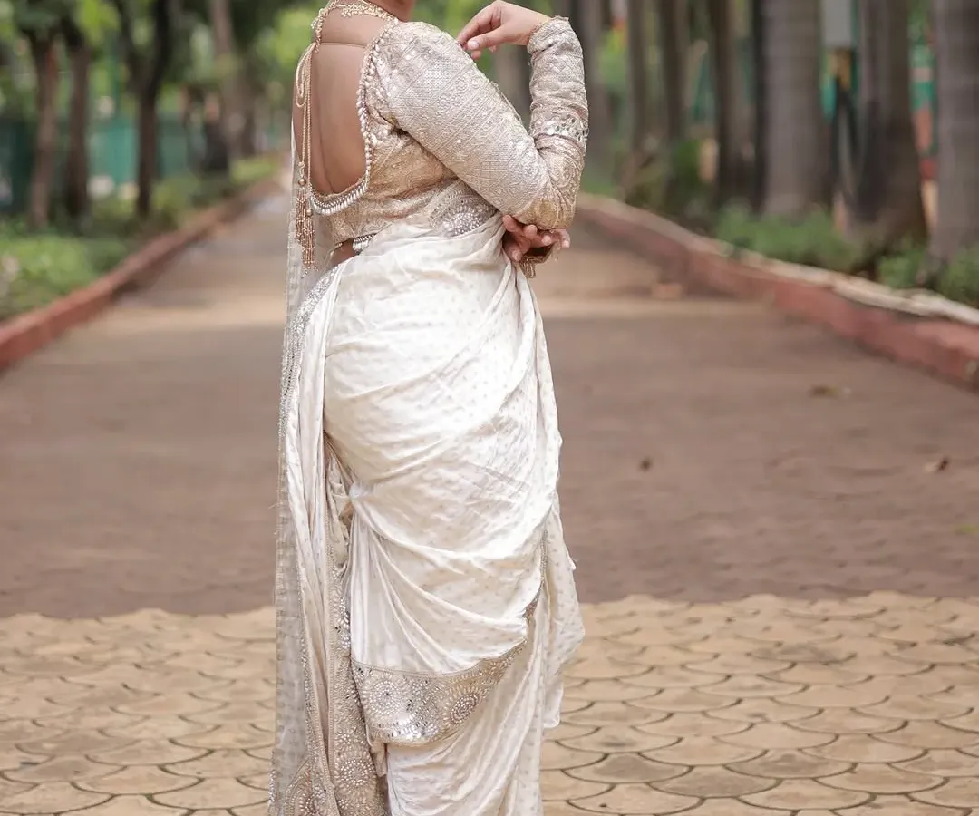 This is for my Maharashtrian brides. This elegant white Nauvari saree offers a modern twist on a timeless tradition. Its dhoti style drape is both comfortable and incredibly graceful, perfect for making a unique statement.