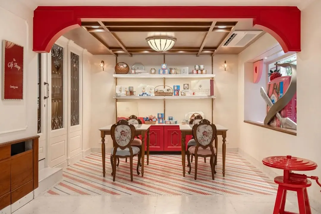 For the Parsi Dairy Farm renovation, I wanted to create a space that felt familiar yet fresh. This gifting zone, with its custom red cabinetry and floral upholstered chairs, is a cozy corner where customers can assemble hampers or enjoy a treat. It’s a perfect example of blending charming, old-world features with a clean, modern aesthetic.