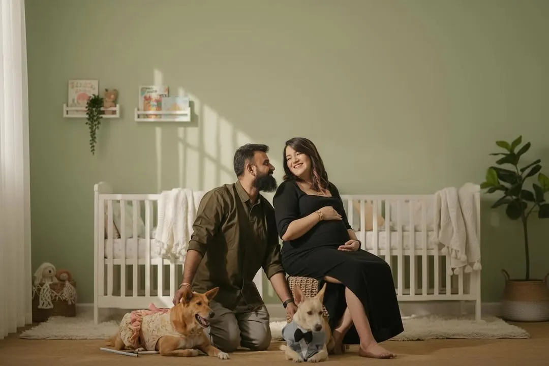 Your whole family is welcome, even the furry members! This is a heartwarming family maternity portrait in my studio's nursery setup, complete with a crib and soft, natural lighting.