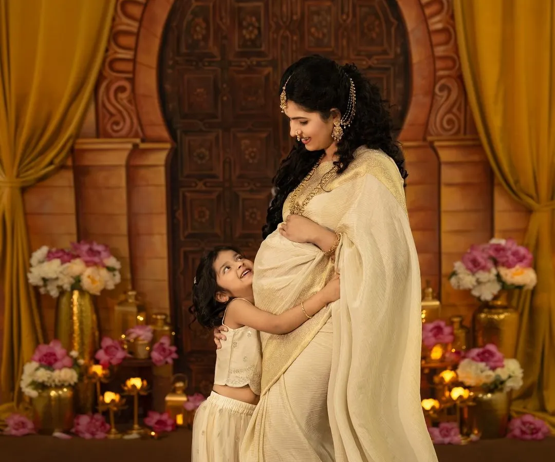 A truly magical moment between a mother and her daughter, eagerly awaiting the new arrival. This maternity session features an elegant, traditional theme with a golden backdrop, rich fabrics, and soft lighting to capture that beautiful pregnancy glow.