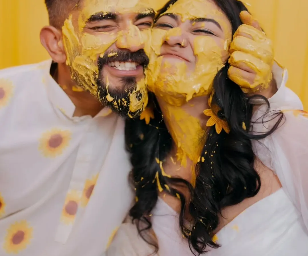 The Haldi ceremony is pure, unscripted fun. I focus on capturing the genuine laughter and playful energy, like this moment where the couple is covered in turmeric paste, completely lost in their joy.