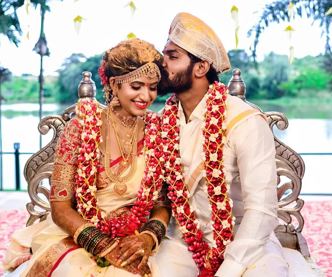 An intimate and tender moment during a traditional South Indian wedding ceremony. The groom's gentle kiss on the bride's forehead captures the pure emotion of the day.