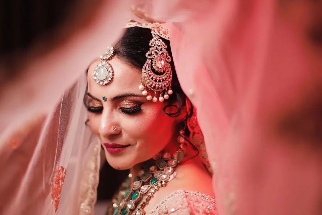 A close-up of one of our brides, capturing the dreamy, romantic look we created. This artistic shot highlights the detailed eye makeup, flawless skin finish, and the perfect placement of traditional jewelry, all essential for a timeless bridal portrait.