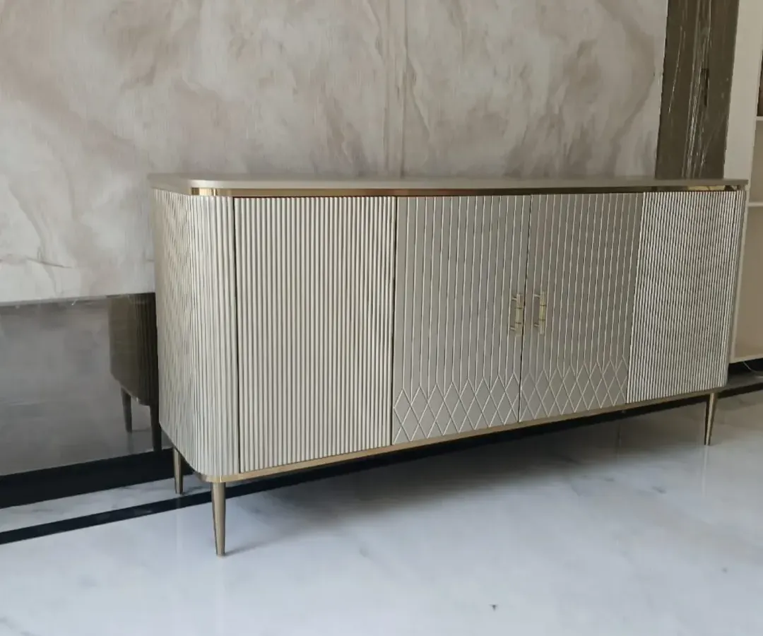 This metallic finish buffet console is a testament to modern elegance. We designed it with clean, fluted textures and fine conical steel legs to create a statement piece that offers both significant storage and a sophisticated aesthetic for dining or living areas.
