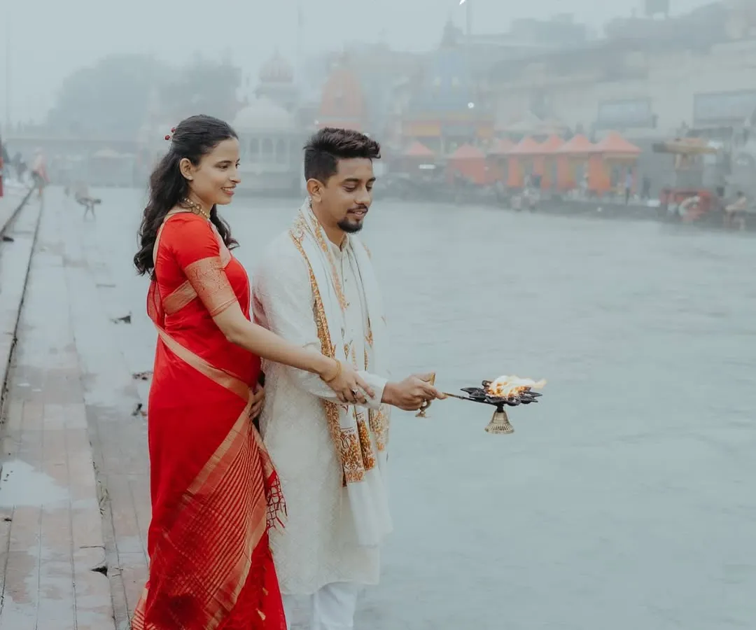 A serene pre-wedding moment on the banks of the Ganga in Haridwar. The quote "Gangechya pavitra paanyat, man shanti" perfectly captures the peace and sanctity of this traditional shoot.