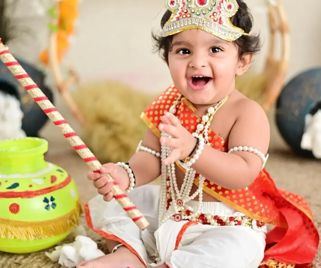 The joy on this little one's face says it all. Our themed shoots, like this popular Little Krishna setup, are all about playful imagination and creating truly unique memories.