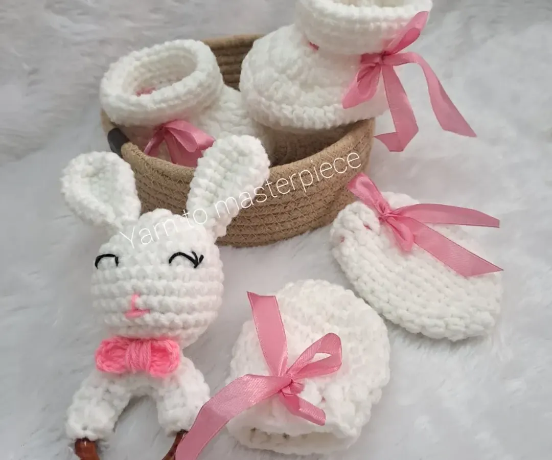 This is my classic newborn gift hamper, a perfect welcome-home present. It features a pair of soft booties, matching no-scratch mittens, and an adorable bunny rattle, all handmade with baby-safe yarn and presented in a reusable basket.
