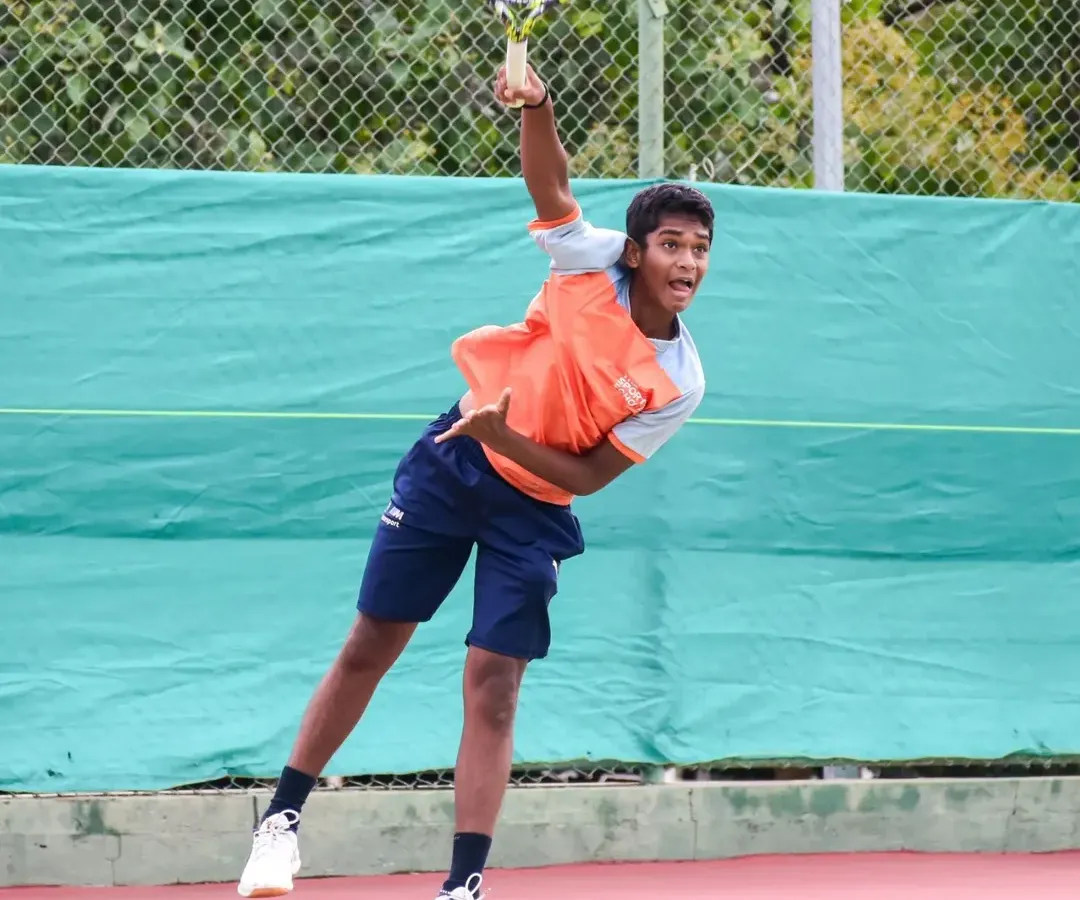 A young tennis player executes a powerful serve, capturing the explosive energy and technical precision we instill in our athletes through our high-performance tennis program.
