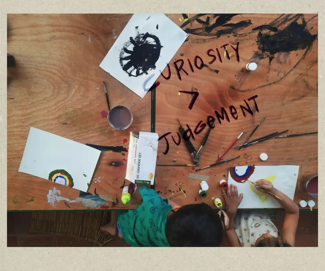 This is the heart of our philosophy: Curiosity over Judgement. In this overhead view of a children's art session, you can see the free exploration and creative expression that we encourage in all our workshops, fostering a safe space for self-discovery without fear of mistakes.