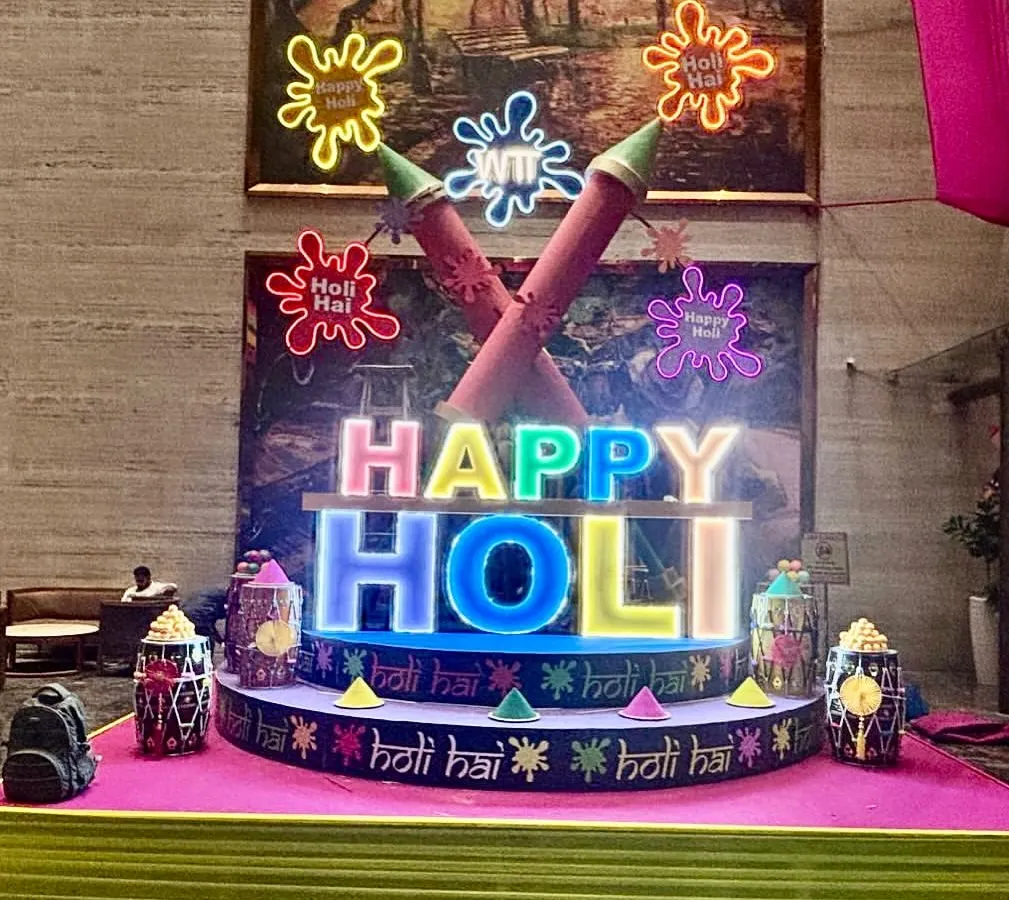 We created this vibrant, large-scale installation for a Holi celebration, featuring custom-lit 'Happy Holi' lettering and oversized pichkari props. This type of illuminated centerpiece becomes the focal point for any festive corporate or private gathering.