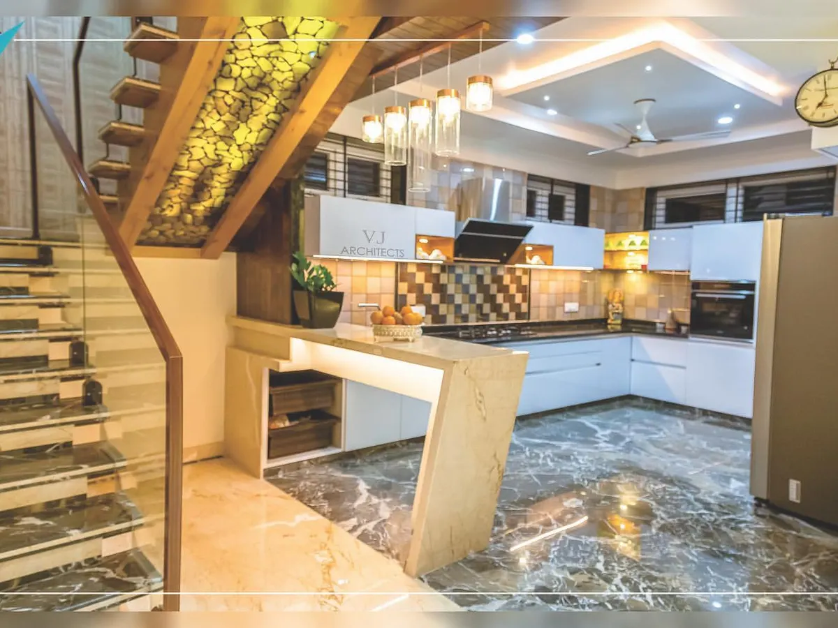We designed this open-plan kitchen to be the heart of the home. It features a marble-finish floor, a functional breakfast counter, and custom cabinetry, all seamlessly integrated with the home's main staircase, which includes unique backlit onyx stone details.