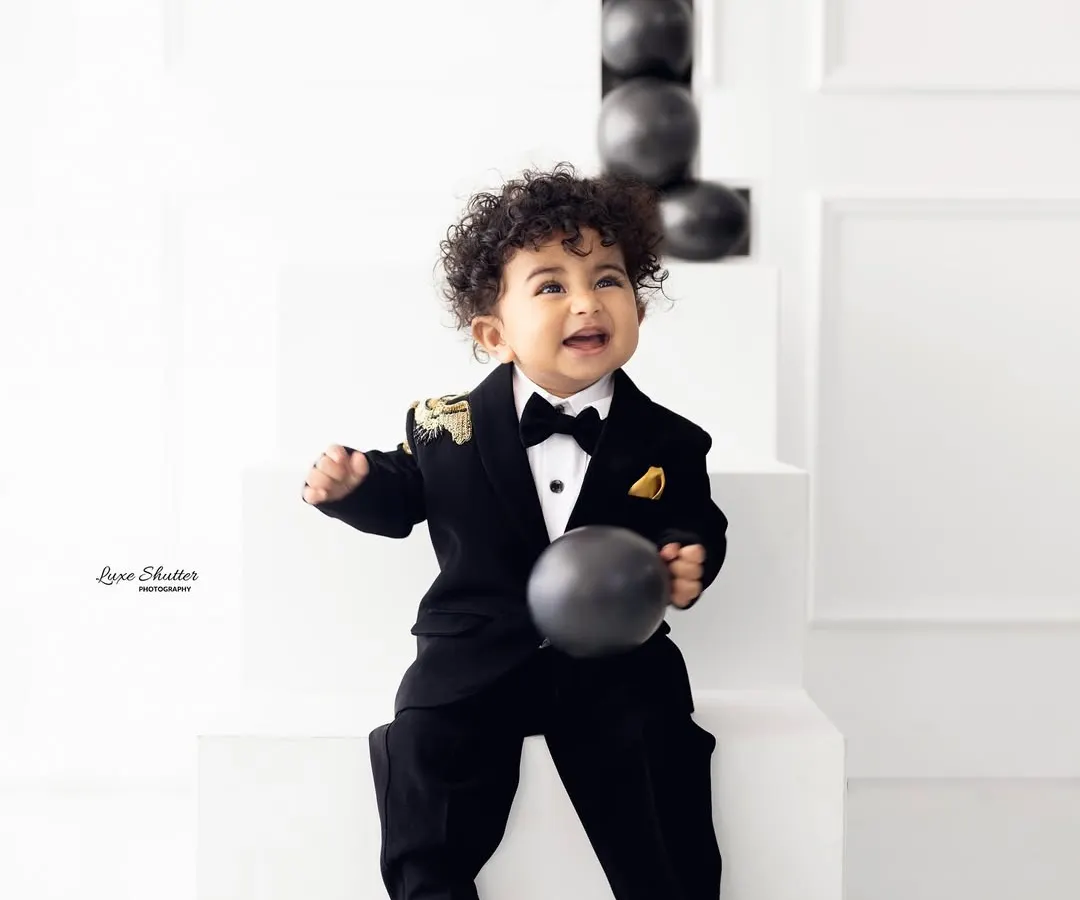 Celebrating a first birthday in style. This little gentleman is all smiles in his sharp tuxedo, showing that milestone sessions can be both fun and incredibly dapper.