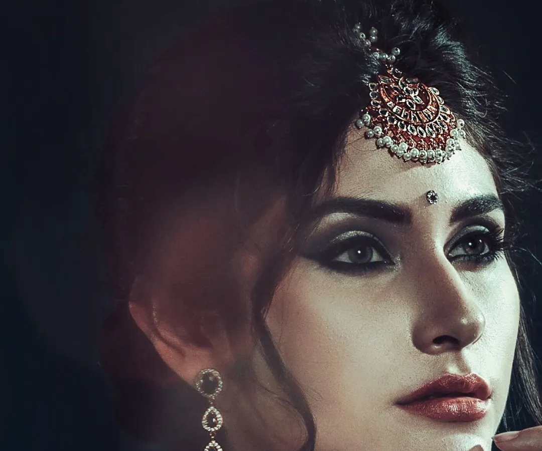 For me, accessory photography is about creating an entire mood. This close-up highlights the intricate design of a traditional maang tikka, using dark, contrasting light to draw attention to the piece and the model's expressive eyes.
