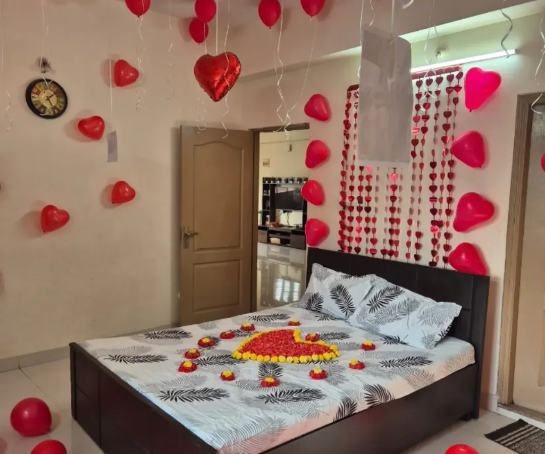 A classic romantic room surprise, perfect for anniversaries or just because. The decoration includes a heart made of flower petals on the bed, with red heart-shaped foil and latex balloons filling the room to create a warm, loving atmosphere.