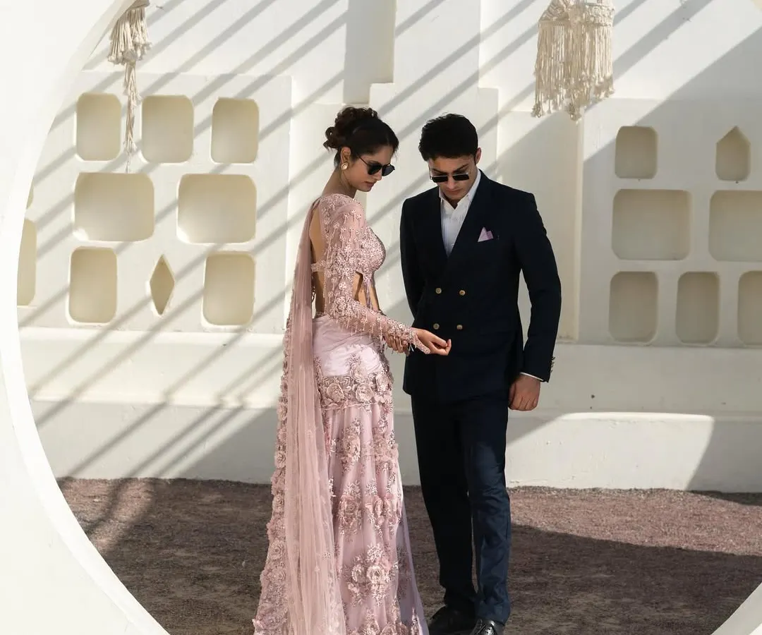 We love styling couples. Here’s a perfect example of a modern, coordinated look with a stunning pale pink embroidered saree for her and a sharp navy double-breasted suit for him. This is how you create memories that look as good as they feel.