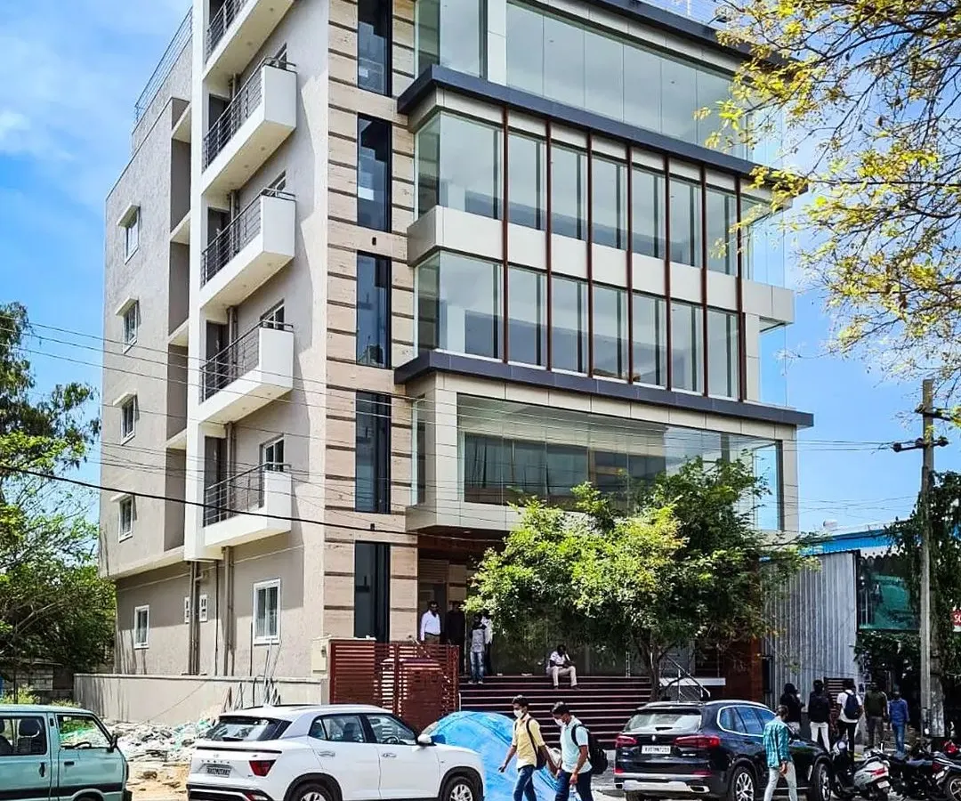 The completed commercial building for Mr. Shivaram in HSR Layout, a bustling commercial hub in Bangalore. This structure features a prominent multi-story glass facade, a signature element of our modern architectural style, designed to maximize natural light and create a strong street presence.
