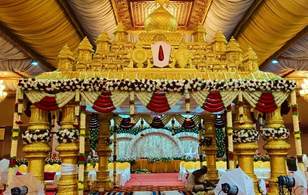 For a truly royal wedding, we designed this grand Muhurtham mandapam, inspired by traditional temple architecture. The intricate gold structure, combined with red and white floral garlands, creates a sacred and opulent space for the main ceremony.