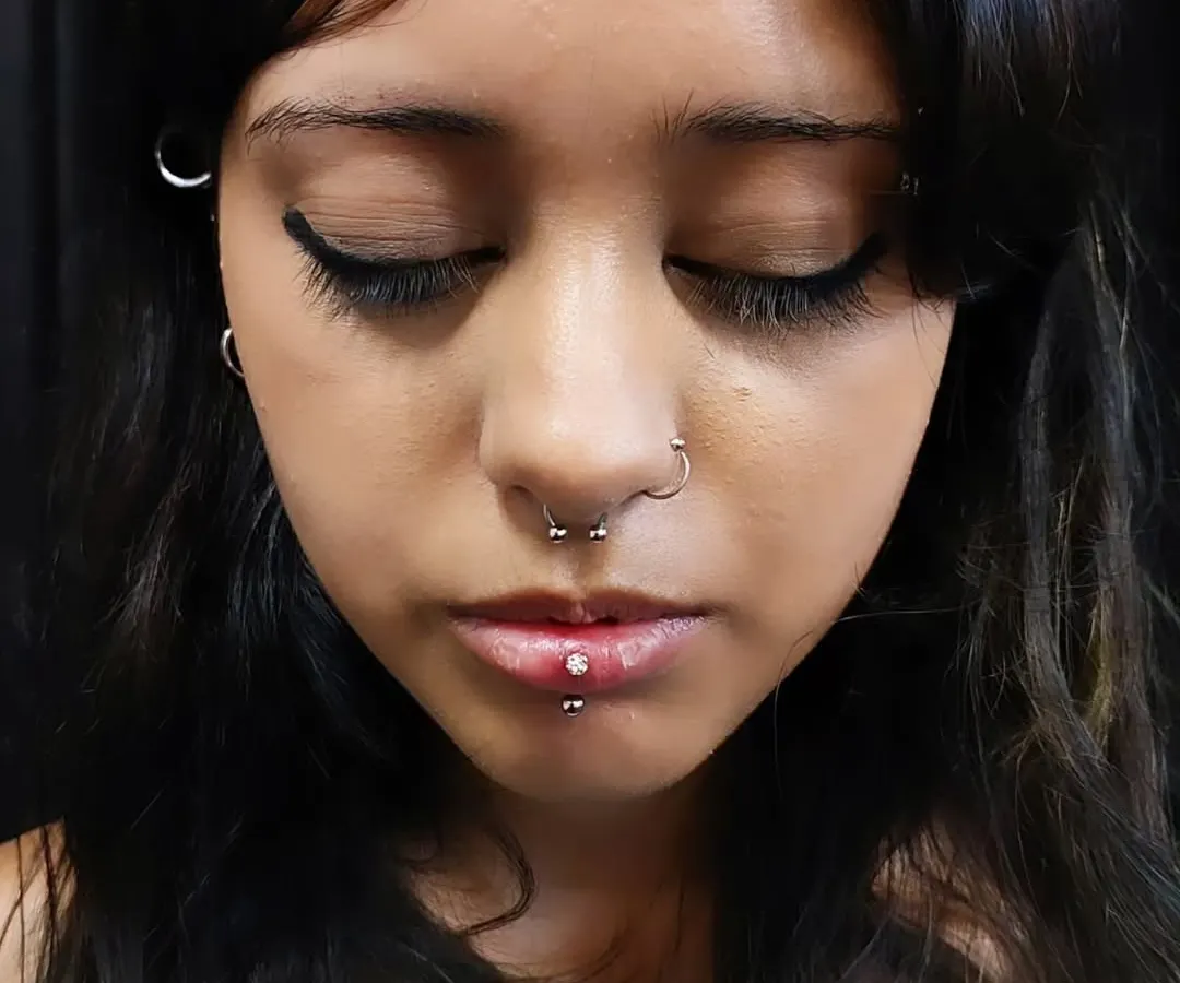 A curated set of facial piercings for a bold look, including a septum ring and a vertical labret piercing. I help you choose jewelry and placement to best suit your style.