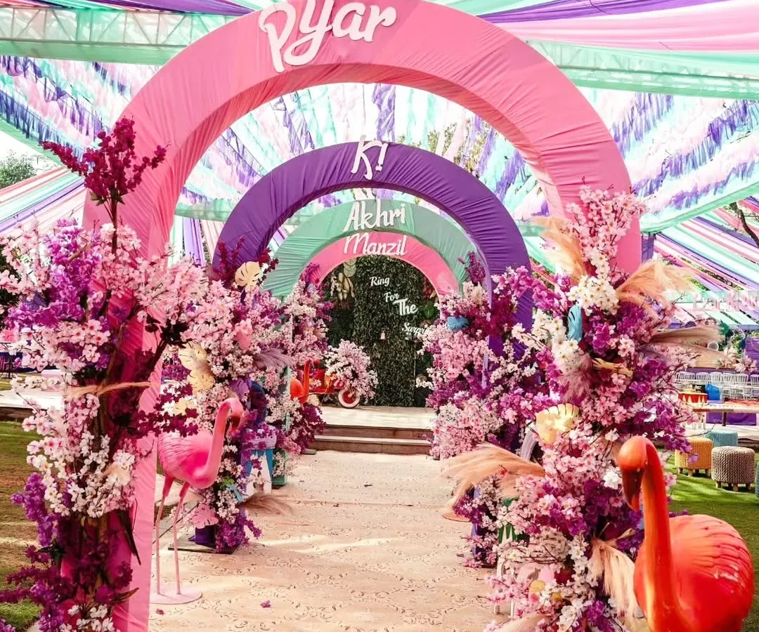 Step into a world of pure joy with an entrance that sets a vibrant tone. We design immersive experiences like this colorful arched walkway, using fabric draping and floral arrangements to build excitement from the very first moment.