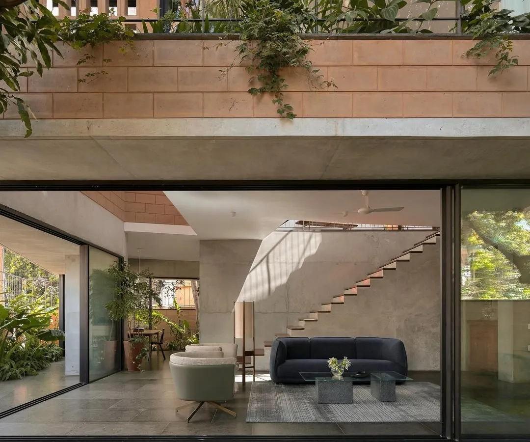 (Hero Media) This is our Debris Block House in Bangalore, where the ground floor opens completely to the landscape. We designed this to maximize the connection to the garden, with light streaming in from skylights and the multi-level open staircase, creating a seamless indoor-outdoor living experience.