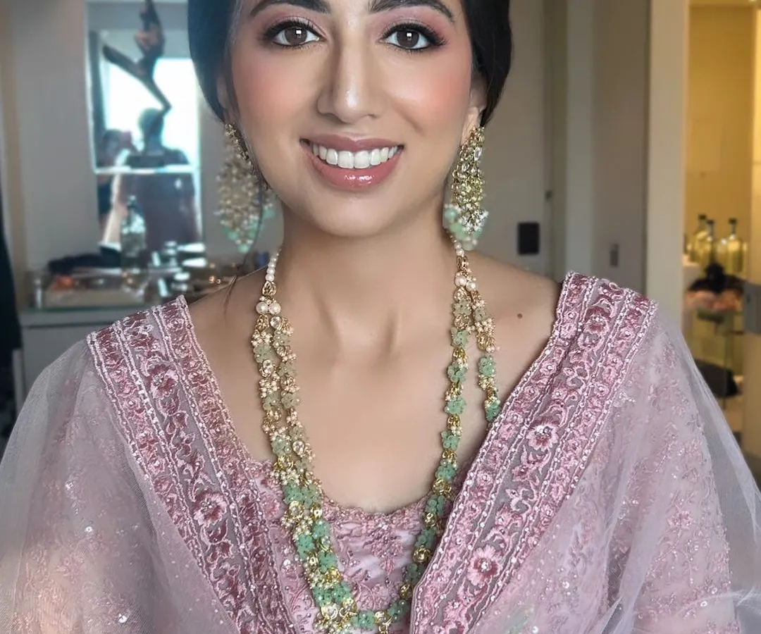 A close-up of a happy client ready for a wedding celebration. We focused on a soft pink monochromatic makeup look to harmonize with her pastel pink outfit, creating a fresh, dewy, and timeless appearance.
