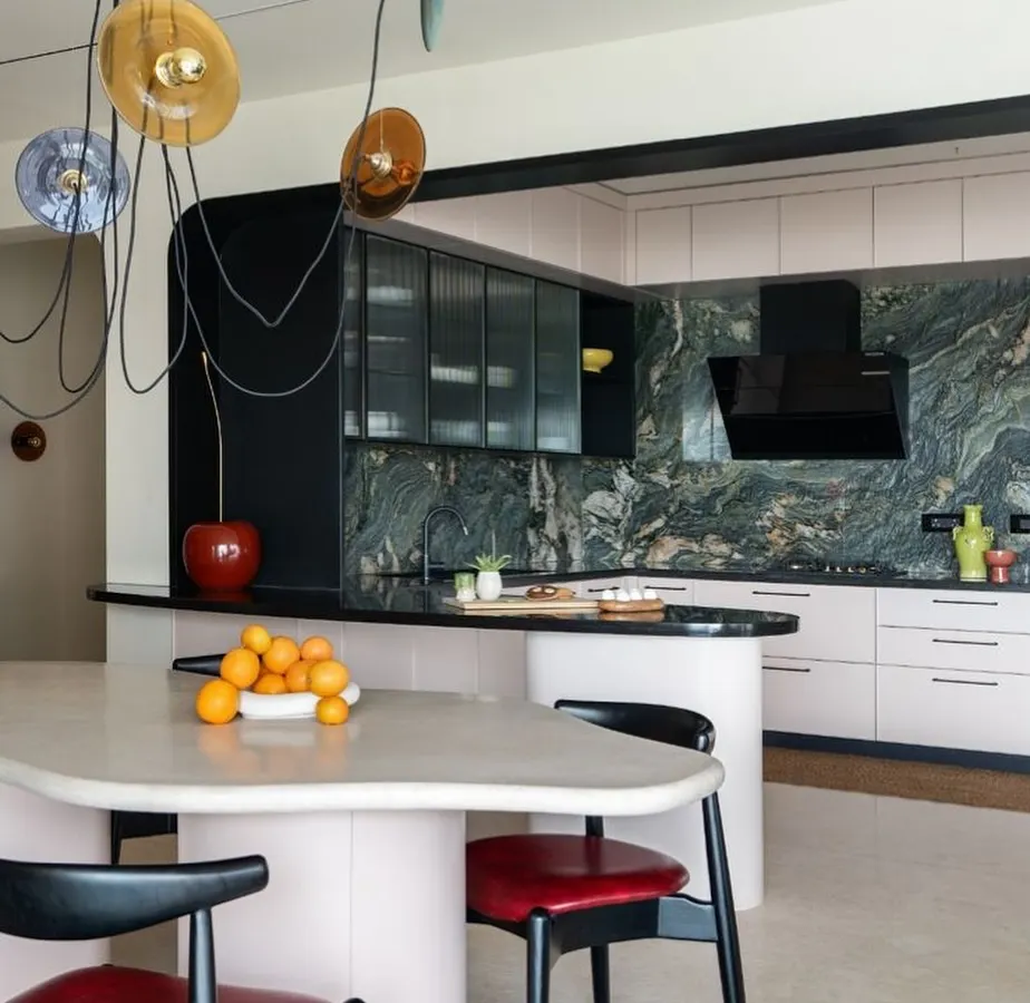For this Bangalore home, the goal was to be bold, eccentric, and fun. This open-plan dining and kitchen area uses flowing furniture, pops of color, and a dramatic marble backsplash to create an informal and energetic family lounge. It’s a perfect example of how I blend unique art-like elements with everyday functionality.
